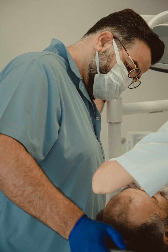 Prosthodontist examining a patient while a denture model and impression tray sit nearby.